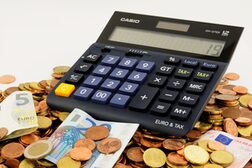 Ein Taschenrechner und Kleingeld sowie Euroscheine