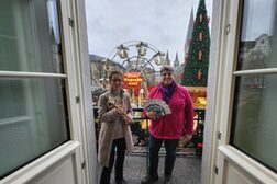 Das Bild zeigt Melanie von Seht, Leiterin der Bonn-Information, und ihre Stellvertreterin Birgit Landsberg auf dem Balkon der Alten Post mit Blick auf Weihnachtsmarkt auf dem Münsterplatz.