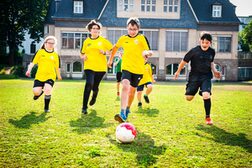 Geistig beeinträchtigte Jugendliche beim Fußballspielen auf einer Rasenfläche