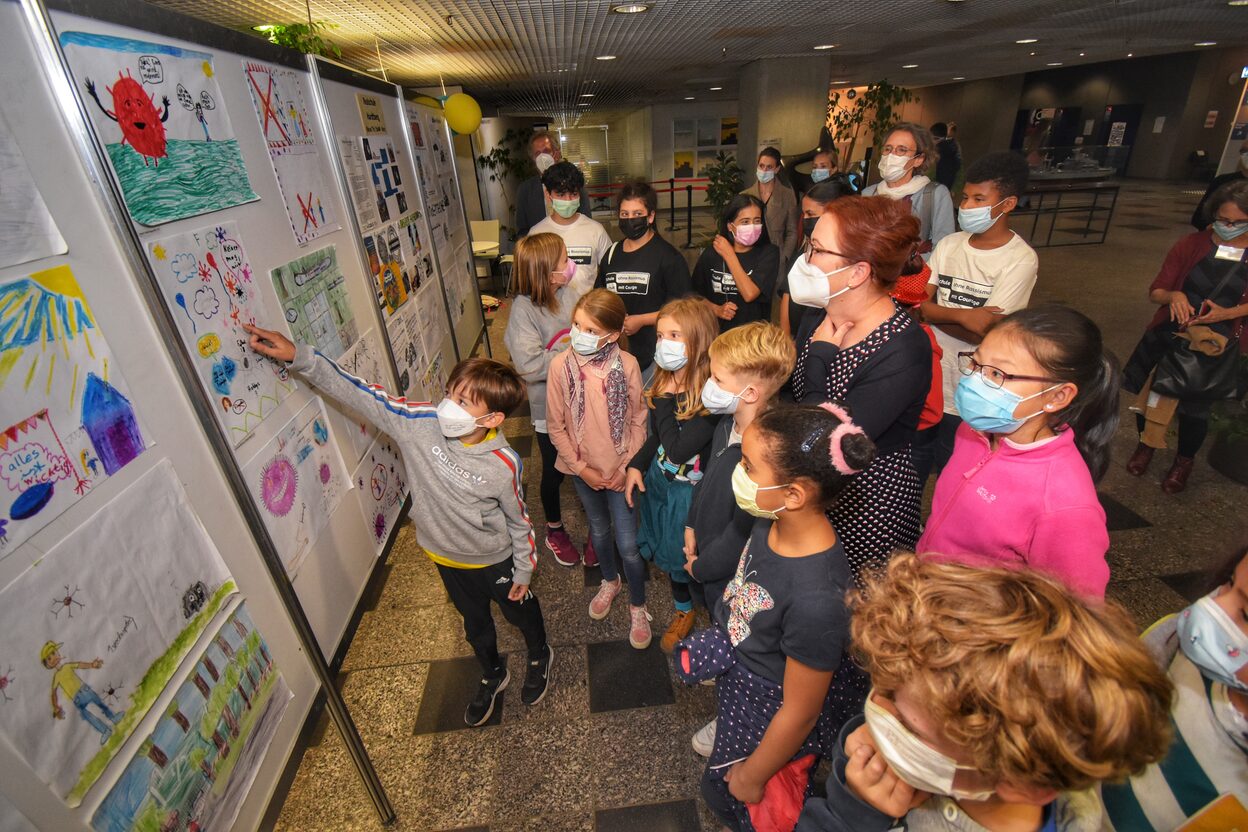 Oberbürgermeisterin Katja Dörner schaut sich gemeinsam mit Kindern die gestalteten Plakate zum Weltkindertag an.