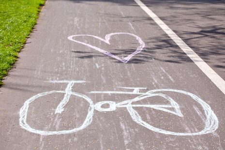 Ein mit Kreide gezeichnetes Fahrrad und ein Herz auf einem Radweg