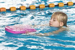 Ein Mädchen beim Schwimmunterricht mit Schwimmbrett
