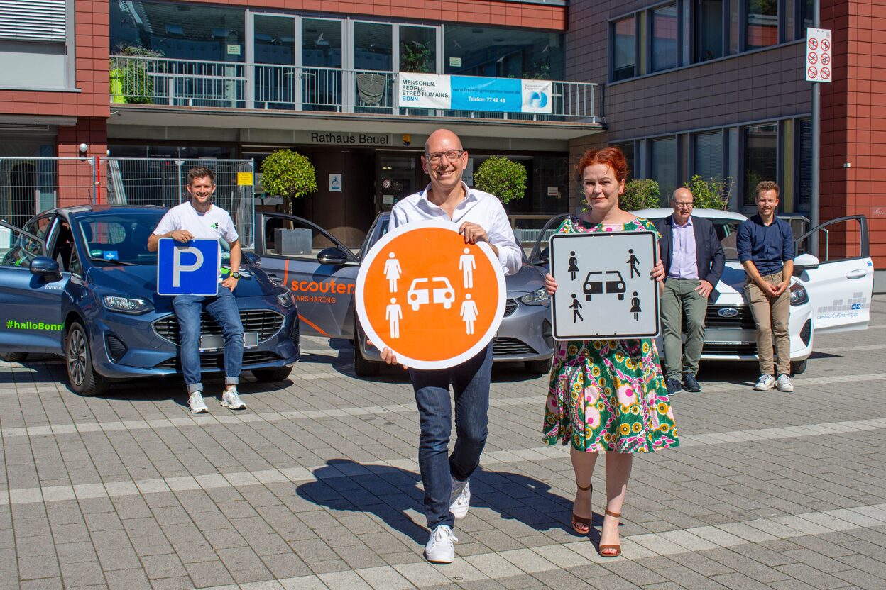 Vertreter der drei Anbieter präsentieren mit der Stadtspitze vor Fahrzeugen auf dem Platz vor dem Beueler Rathaus das stationäre Carsharing-System.