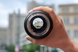Das Stadthaus durch ein Kamera-Objektiv, das in einer Hand gehalten wird, fotografiert.