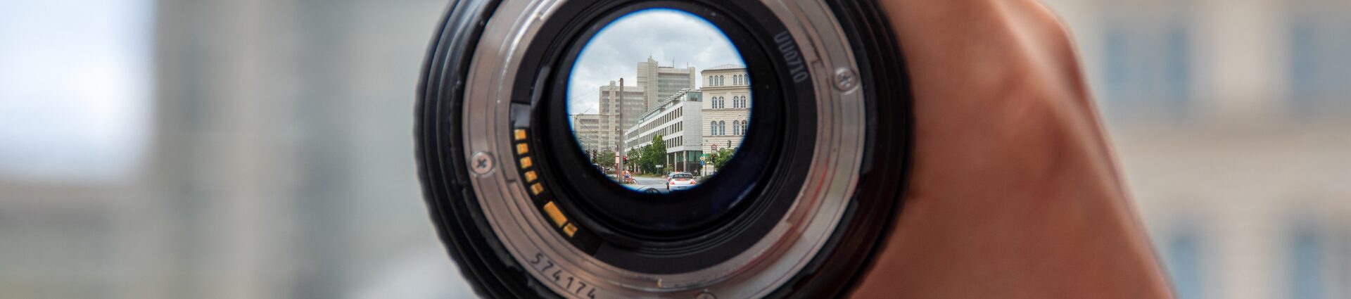 Das Stadthaus durch ein Kamera-Objektiv, das in einer Hand gehalten wird, fotografiert.
