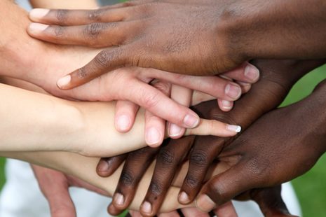 Menschen verschiedener Hautfarben haben ihre Hände übereinandergelegt