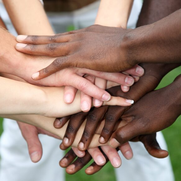 Menschen verschiedener Hautfarben haben ihre Hände übereinandergelegt