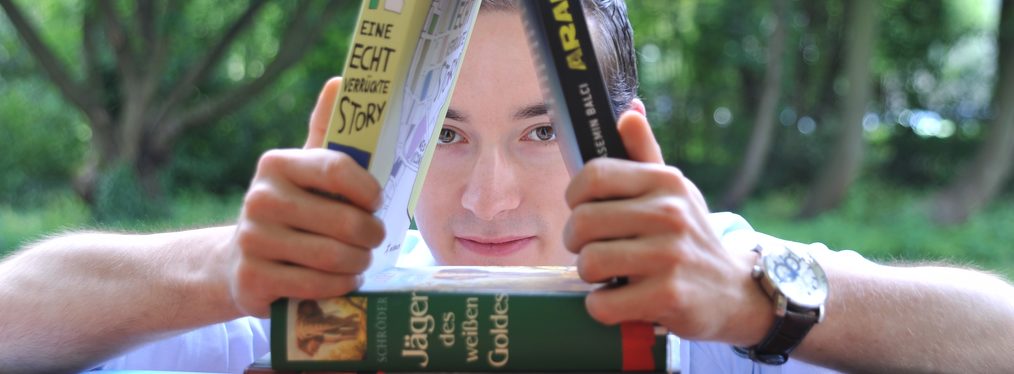 Ein Jugendlicher stapelt Bücher wie ein Kartenhaus aufeinander