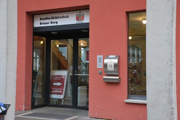 Eingang zur Stadtteilbibliothek Brüser Berg, die in einem rot angestrichenen Gebäude untergebracht ist