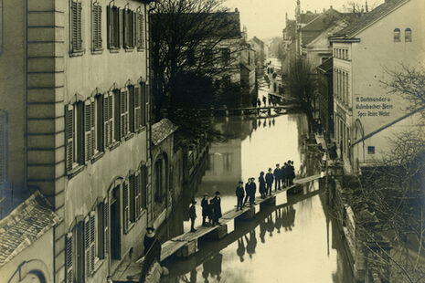 Menschen stehen auf Steg während des Hochwassers in der Rheinaustraße in Beuel am 1. Januar 1926