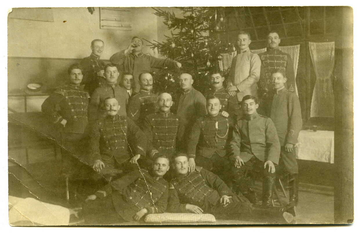 Alte Schwarz-Weiß-Fotografie mit Männern in Uniformen vor einem geschmückten Weihnachtsbaum