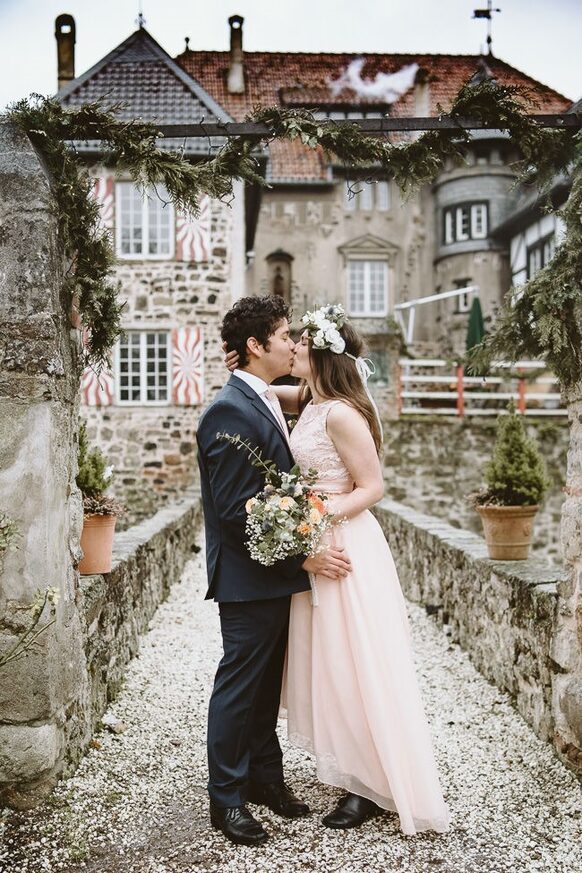 Sich küssendes Hochzeitspaar vor der Burg Lede