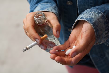 Mädchen hält Zigarette, Medikamente und Alkohol in den Händen