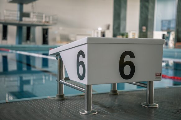 Ein Startblock mit der Nummer Sechs an einem Schwimmbecken.