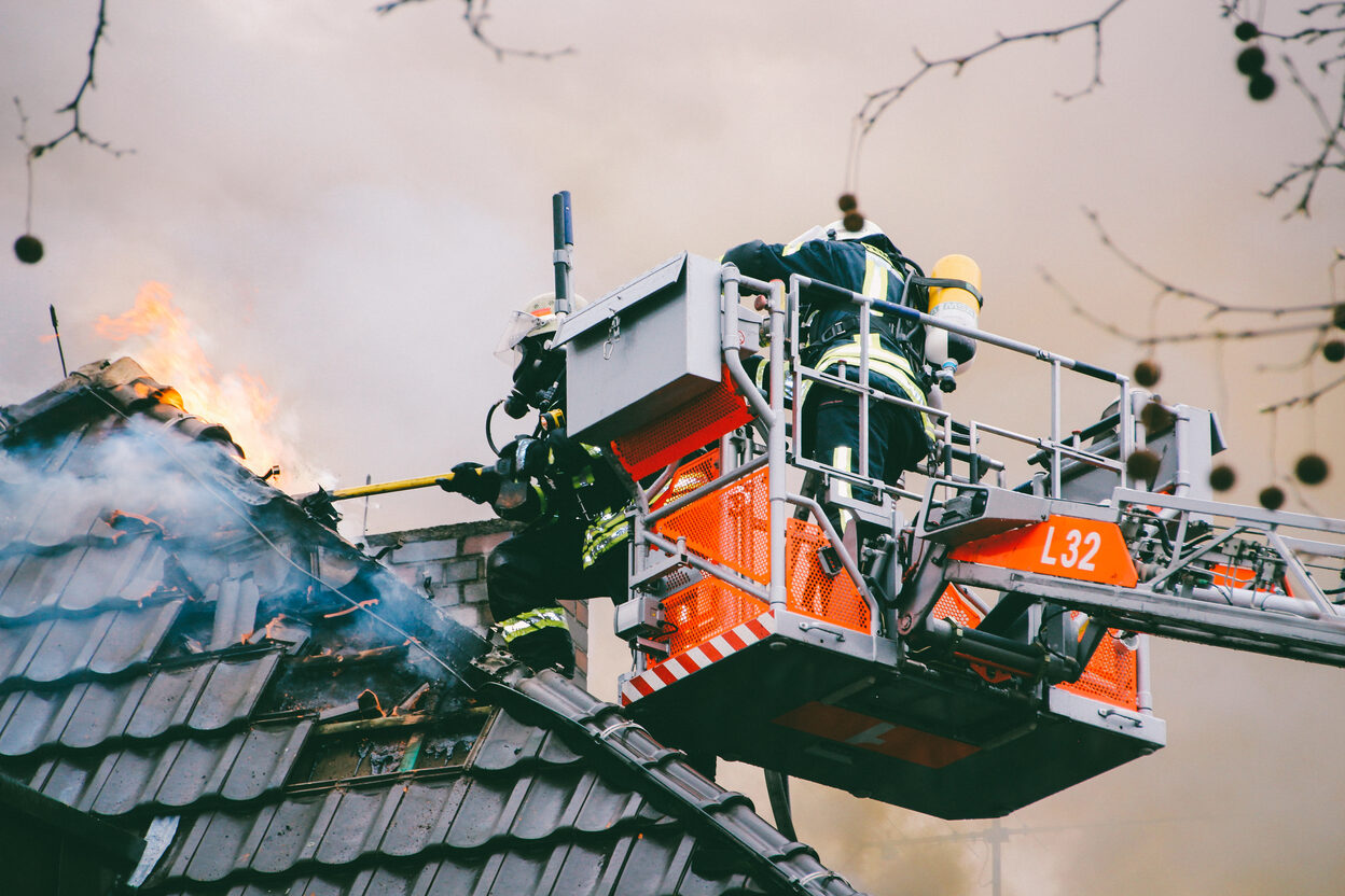 Feuerwehrleute auf einer Drehleiter löschen einen brennenden Dachstuhl