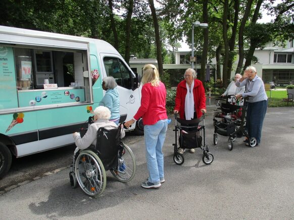 Seniorinnen und Senioren stehen vor einem Eiswagen Schlange