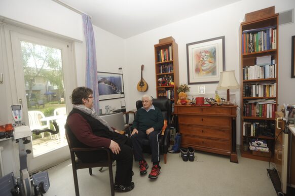 Ein Senior empfängt eine Besucherin in seinem Zimmer