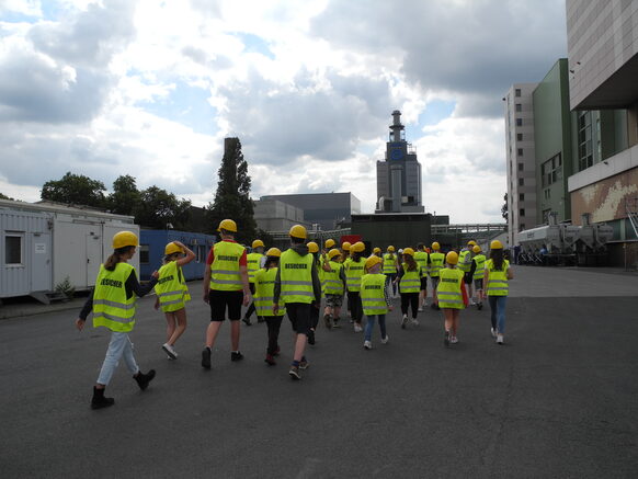 Gruppe von Kindern mit gelben Warnwesten auf dem Gelände der Müllverwertungsanlage Bonn.