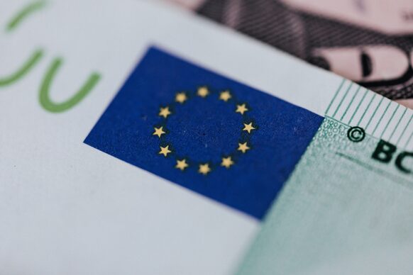 Nahaufnahme der Europaflagge mit den gelben Sternen auf blauem Grund auf einem Euro-Geldschein