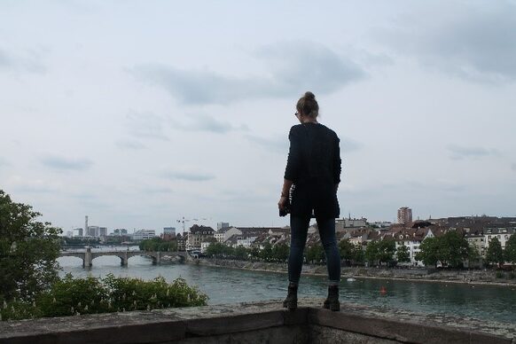 Junge Frau steht am Rheinufer.