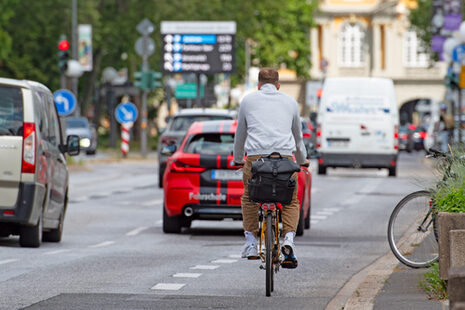 Das Bild zeigt einen Radfahrer, der auf einem Radstreifen neben vielen Autos auf das Koblenzer Tor in Bonn zufährt