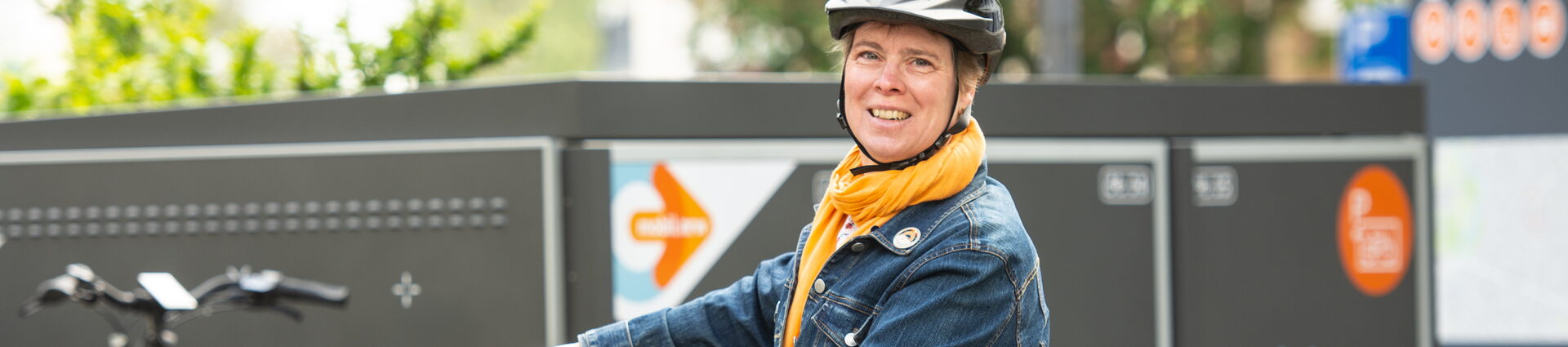 Eine Frau steht mit ihrem Fahrrad vor einer Mobilbox, in der man in Bonn Fahrräder sicher verwahren kann.