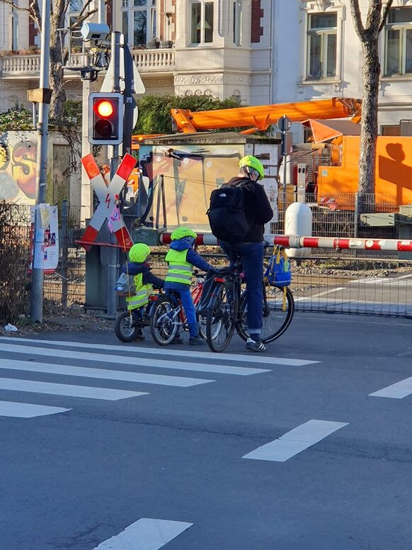 Das Bild zeigt einen Mann und zwei kleine Kinder auf Fahrrädern.
