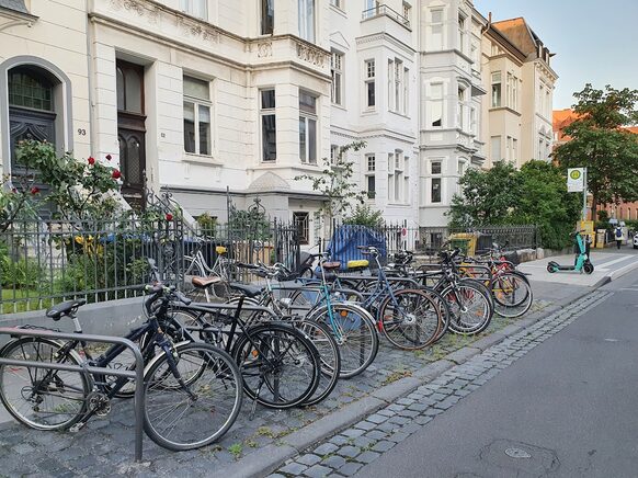 Das Foto zeigt eine Reihe von Fahrrädern, die an Fahrradbügeln angeschlossen sind.