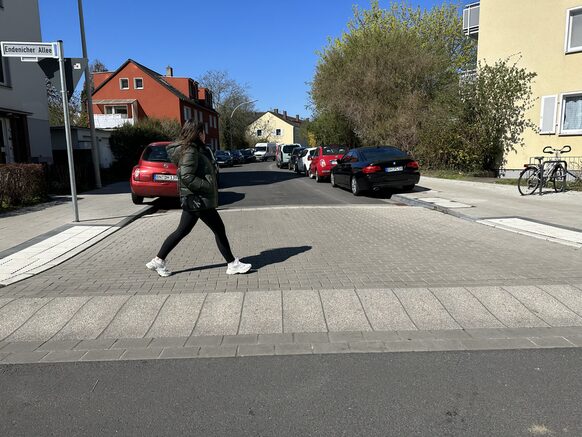 Das Foto zeigt eine Frau, die auf einem neuen, sicheren Fußweg eine Straße quert.