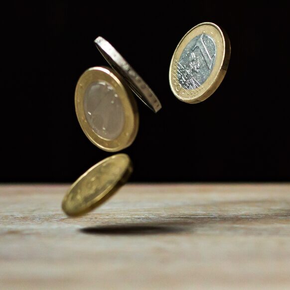 Euro Münzen fallen auf einen "Boden"/Tisch.