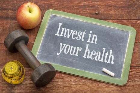Apfel, Maßband, Hantel, Tafel mit Aufschrift "Investiere in deine Gesundheit".