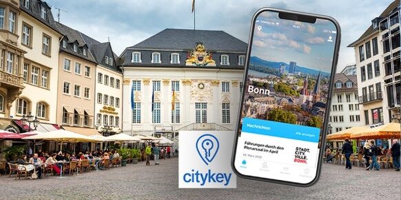 Citykey App auf einem Handy, im Hintergrund das Alte Rathaus