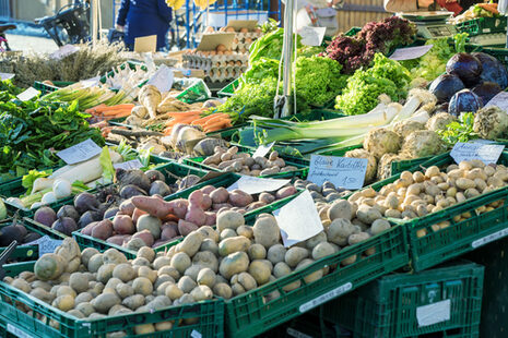 Ein Marktstand mit Kisten voller Kartoffeln und Gemüse