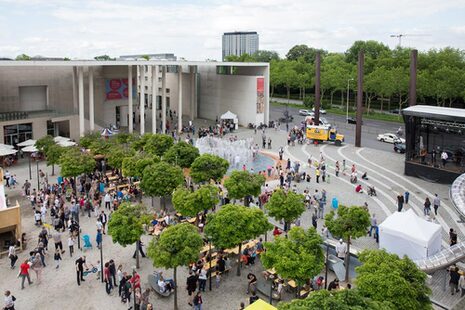Die Luftaufnahme zeigt den mit Menschen belebten Museumsmeilenplatz