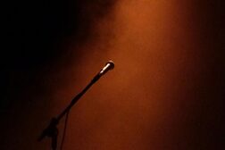 Ein Mikrofon auf der Bühne mit dunklem Hintergrund und ein bisschen Rauch