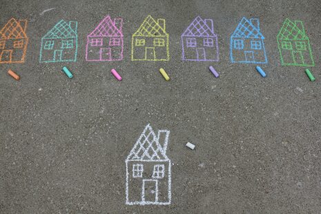 Mit bunter Kreide auf Straßenbelag gemalte Häuschen